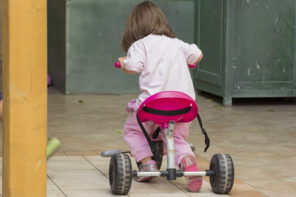 Bambina di spalle sul triciclo