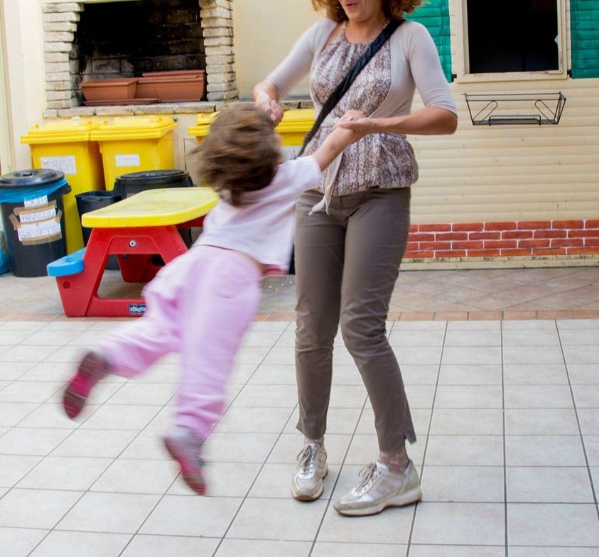 Mamma che fa girare la sua bambina nel cortile